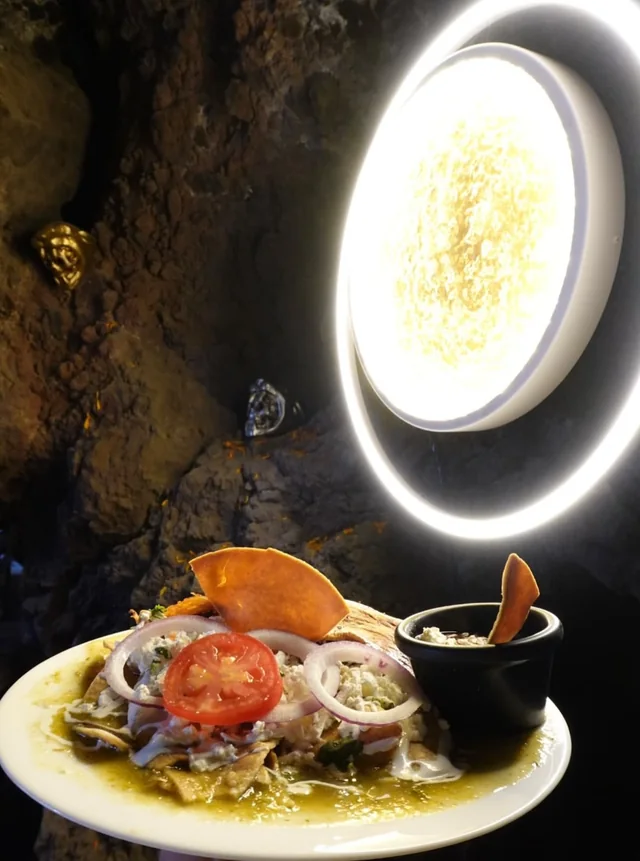 Chilaquiles verdes con jitomate y cebolla, acompañados de salsa en molcajete
