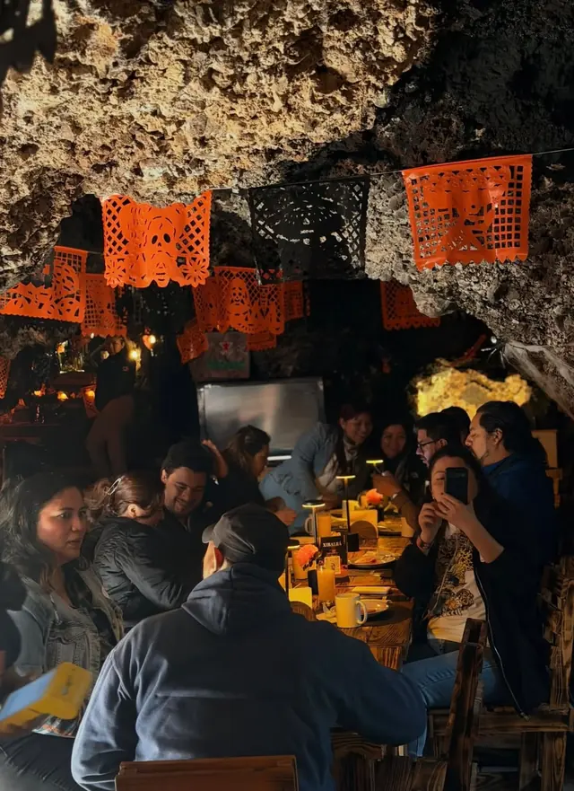 Comensales desayunando bajo papel picado naranja