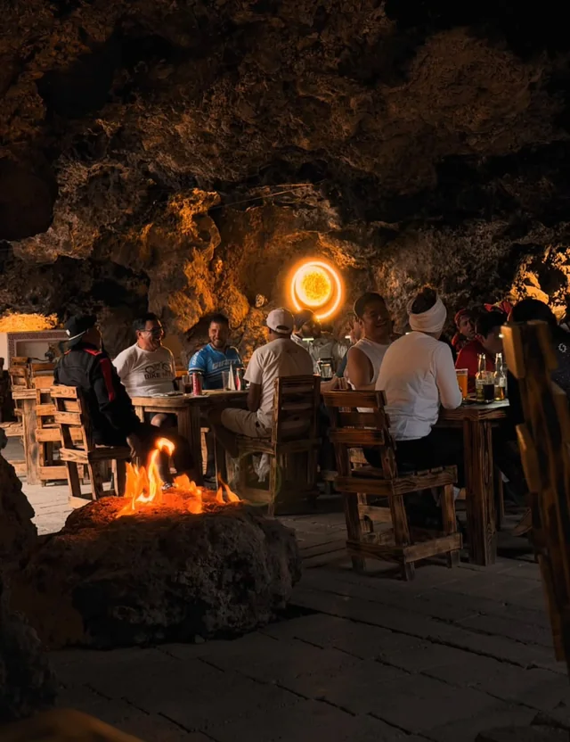 Fogata encendida en el comedor de la cueva, con mesas llenas de visitantes