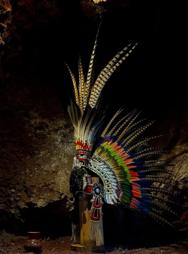 Penacho de plumas de colores iluminado en la oscuridad de la cueva