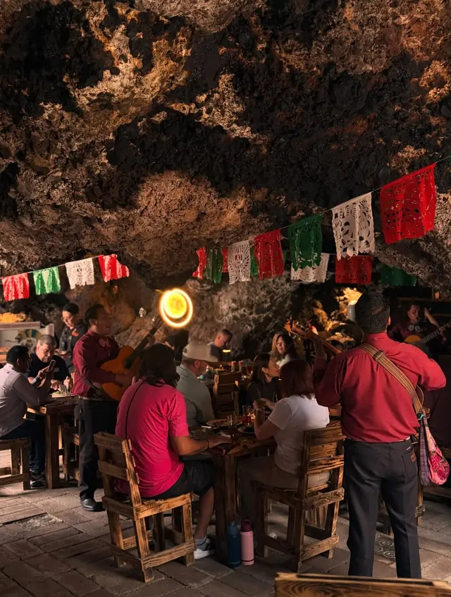 Mariachi tocando entre las mesas del comedor, bajo banderines tricolores