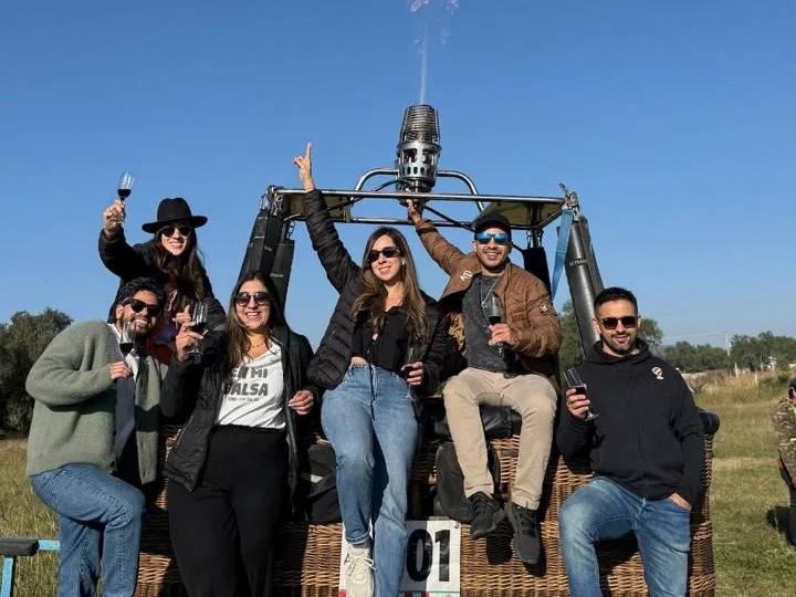 Grupo de amigos brindando sobre la canastilla del globo después del vuelo