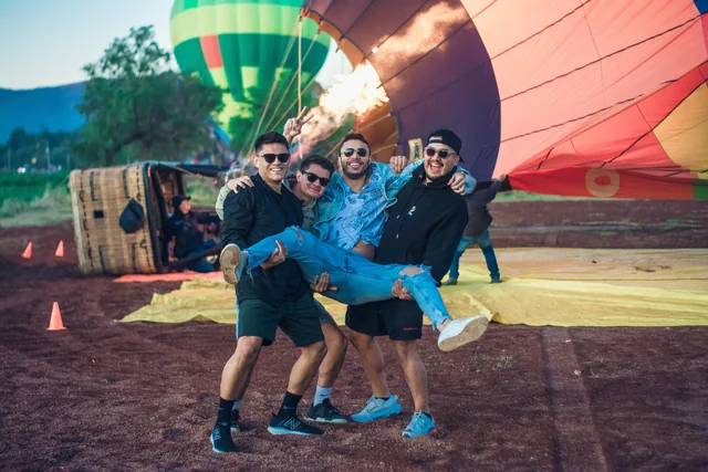 Cuatro amigos bromeando frente a un globo que se infla