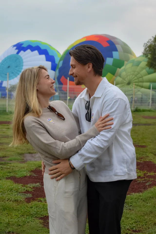 Pareja abrazada frente a varios globos de colores
